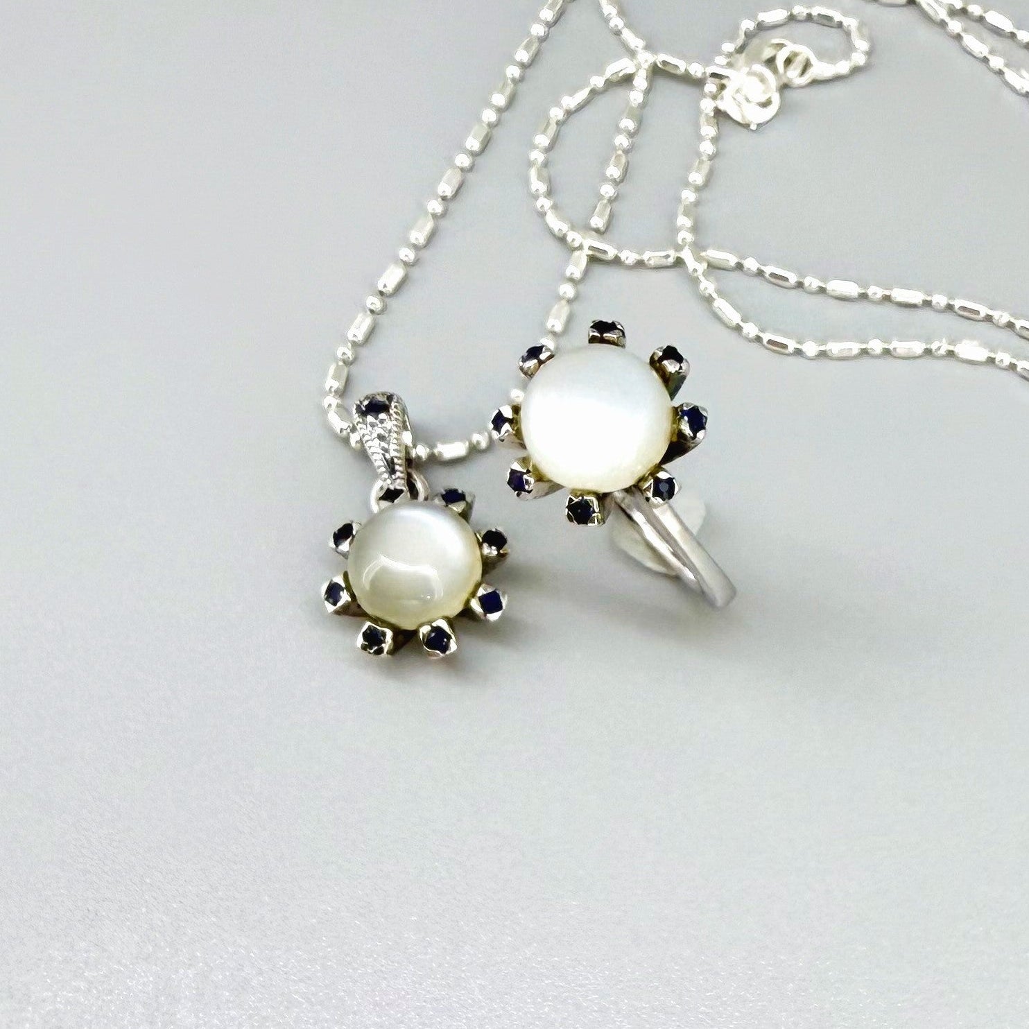 Handcrafted pendant featuring 3.75 ct natural moonstone and 0.35 ct blue sapphires set in white-gold-plated sterling silver.