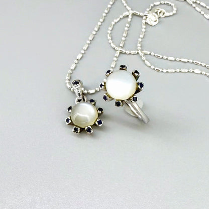 Handcrafted pendant featuring 3.75 ct natural moonstone and 0.35 ct blue sapphires set in white-gold-plated sterling silver.