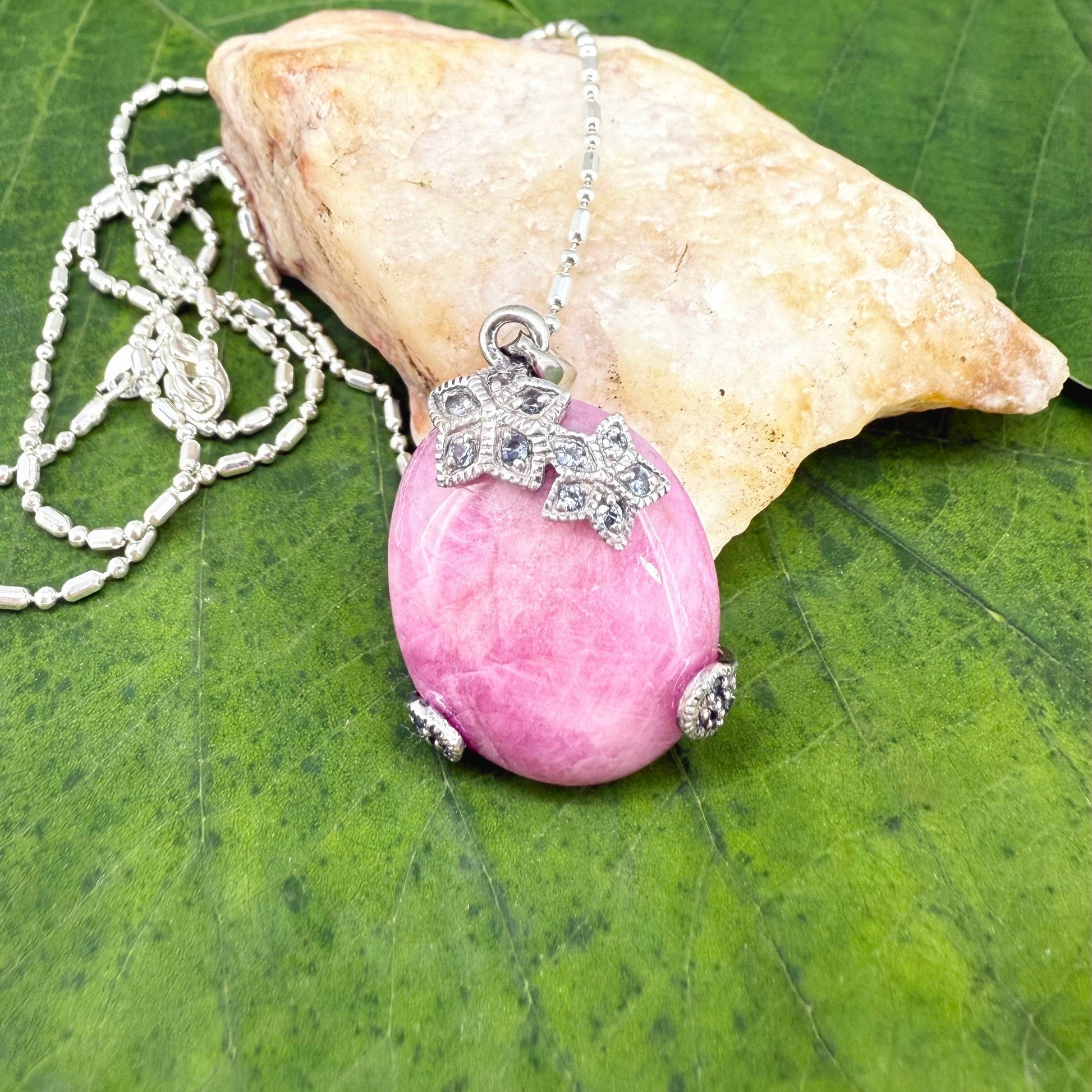 Handcrafted pendant with 46.3 ct natural ruby cabochon and 2.05 ct light blue sapphires in a white-gold-plated silver floral design.