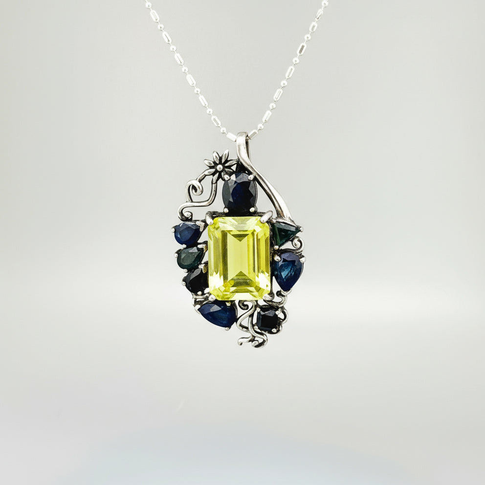 Jewelry pendant with a Lemon Quartz and Blue Sapphire stones on a gray background