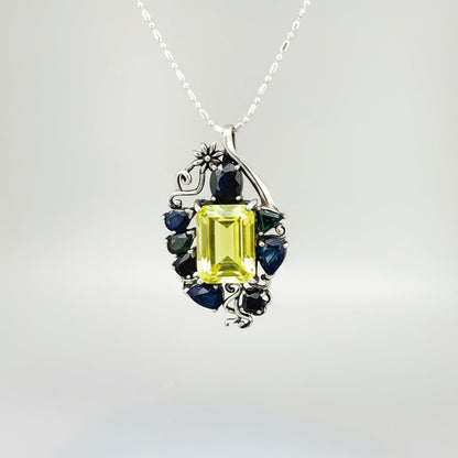 Jewelry pendant with a Lemon Quartz and Blue Sapphire stones on a gray background