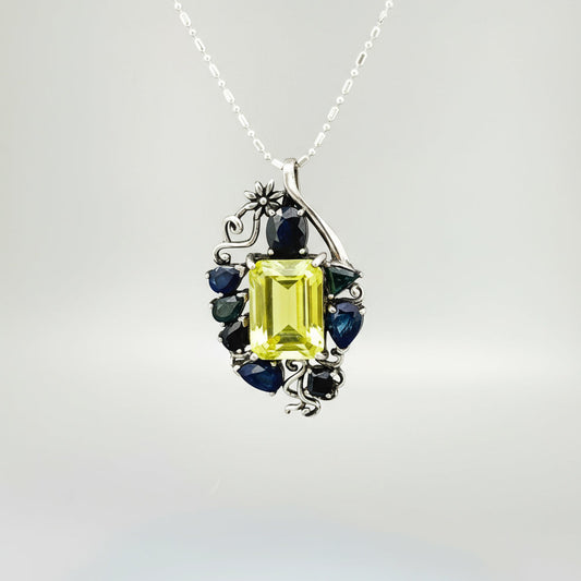 Jewelry pendant with a Lemon Quartz and Blue Sapphire stones on a gray background