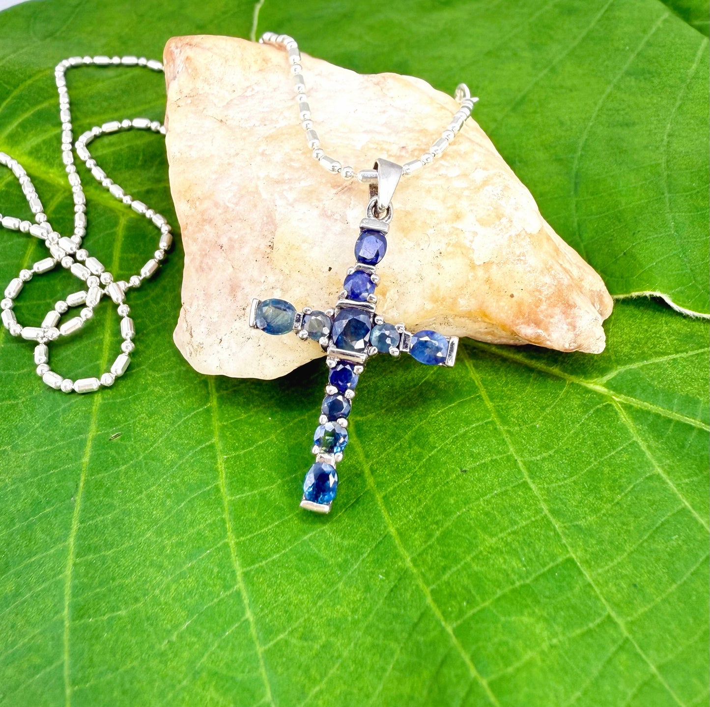 Handcrafted cross pendant with blue sapphires set in white-gold-plated sterling silver.