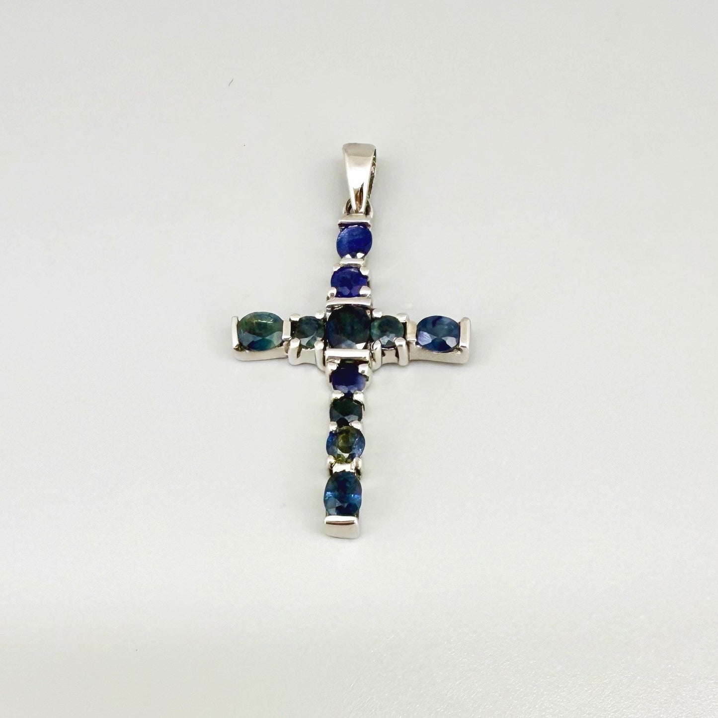 Handcrafted cross pendant with blue sapphires set in white-gold-plated sterling silver.