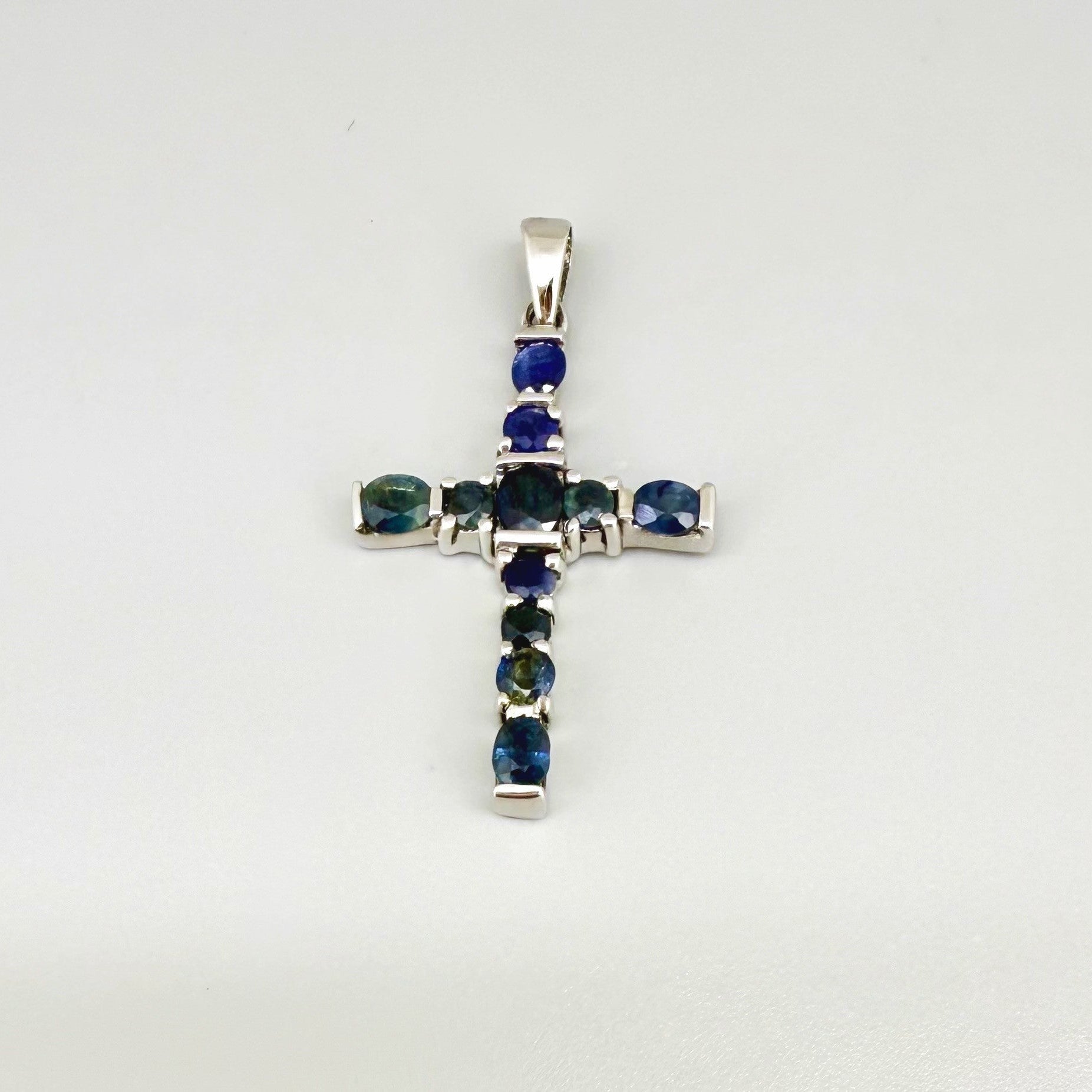 Handcrafted cross pendant with blue sapphires set in white-gold-plated sterling silver.