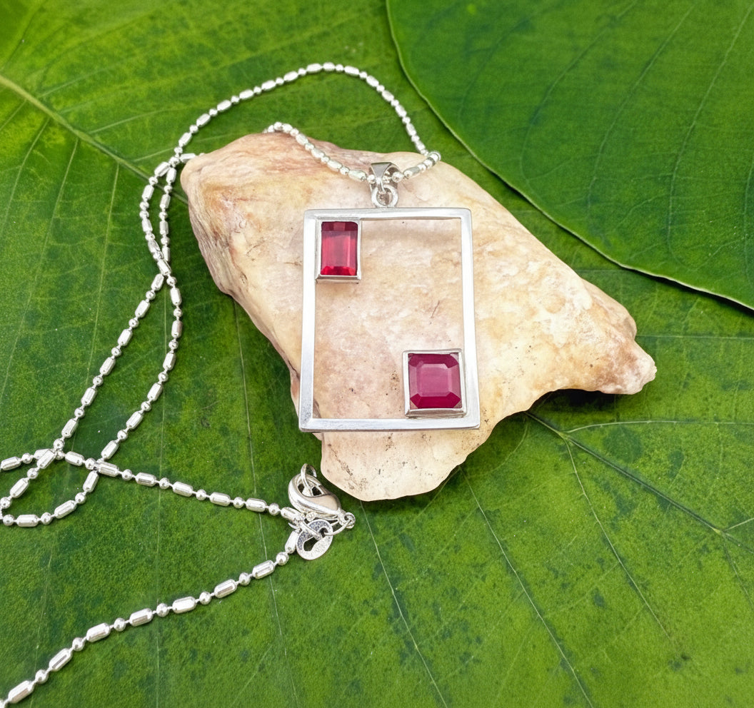 Modern handcrafted silver pendant with two natural rubies (3.24 ct total) set in an open square geometric frame.
