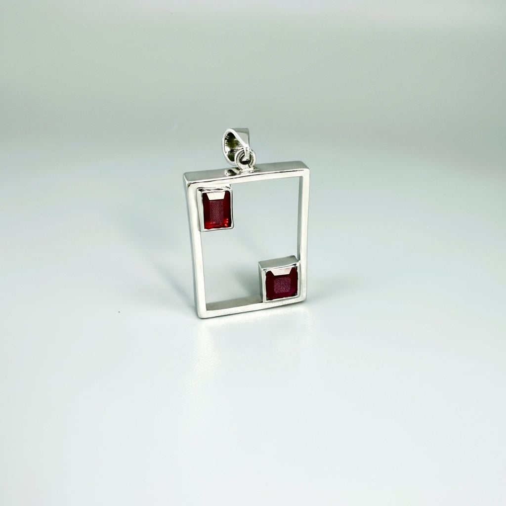 Modern handcrafted silver pendant with two natural rubies (3.24 ct total) set in an open square geometric frame.