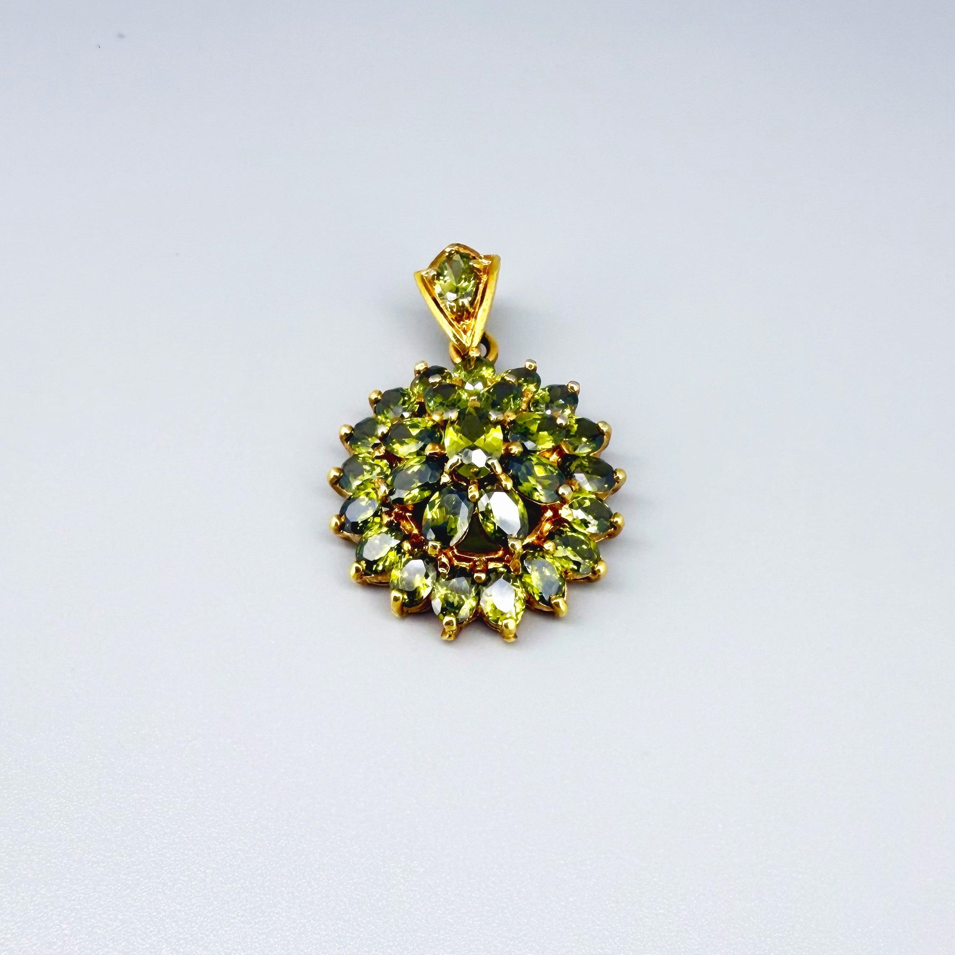 Gold-plated sterling silver pendant with natural green sapphires in a floral-inspired design.