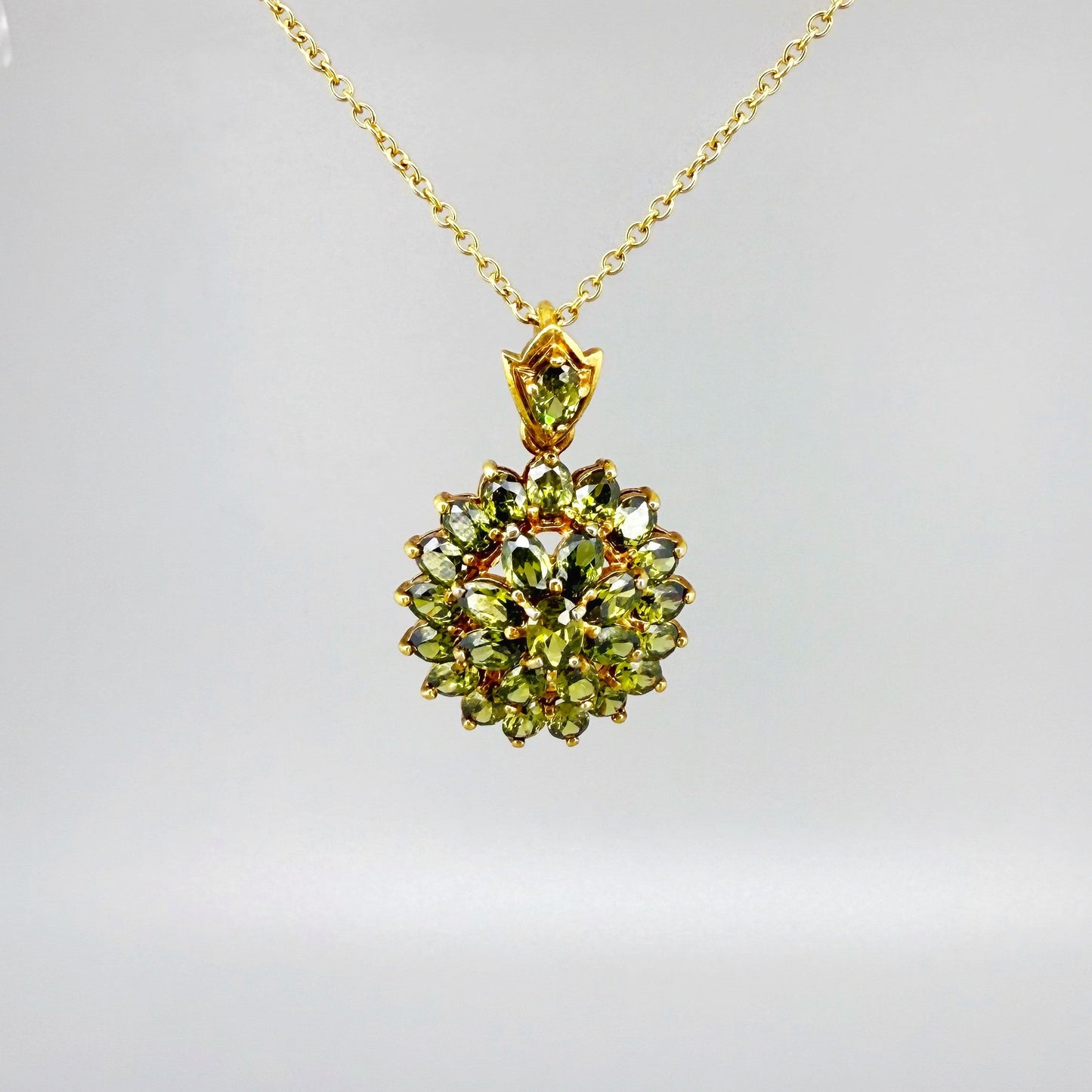 Gold-plated sterling silver pendant with natural green sapphires in a floral-inspired design.