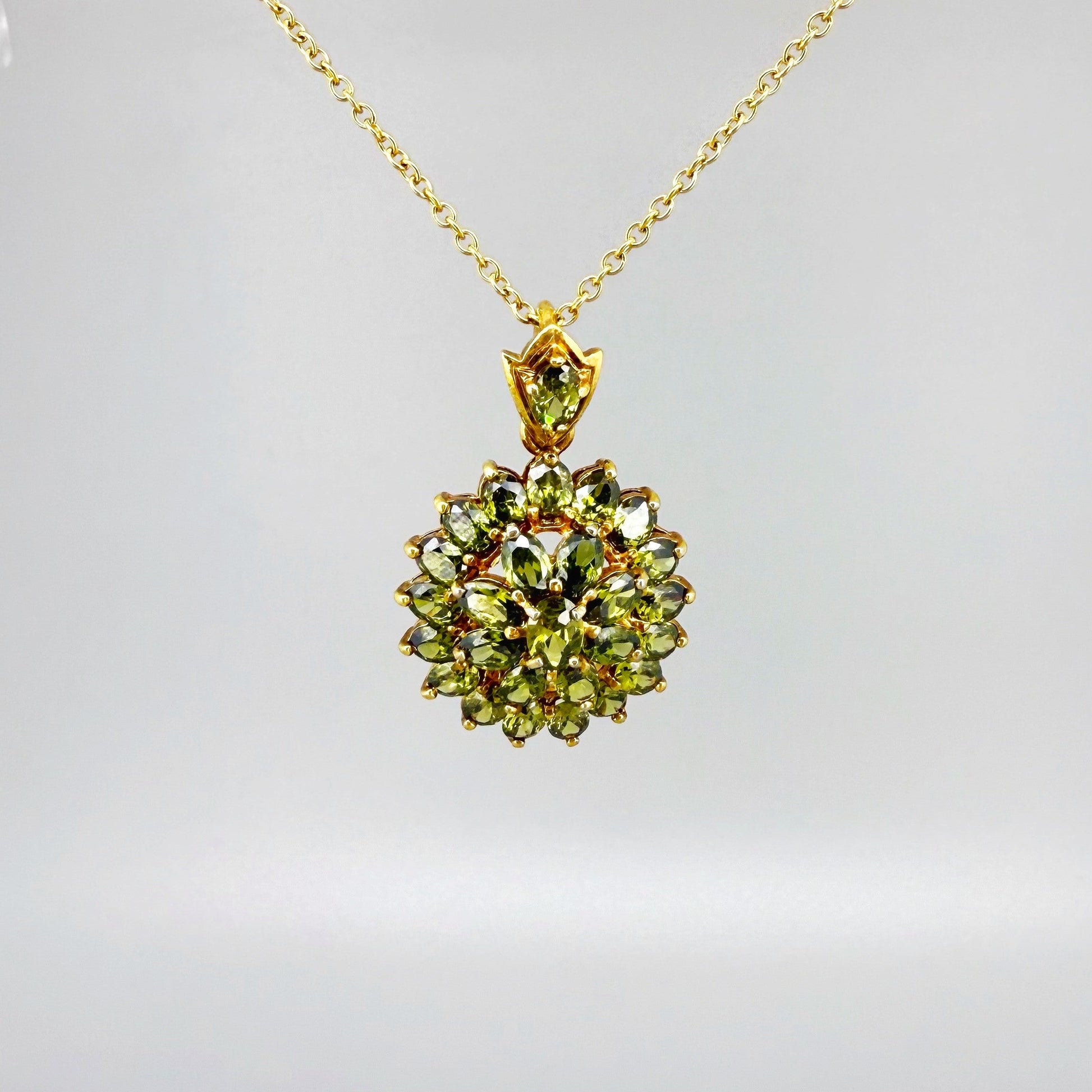 Gold-plated sterling silver pendant with natural green sapphires in a floral-inspired design.