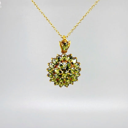 Gold-plated sterling silver pendant with natural green sapphires in a floral-inspired design.
