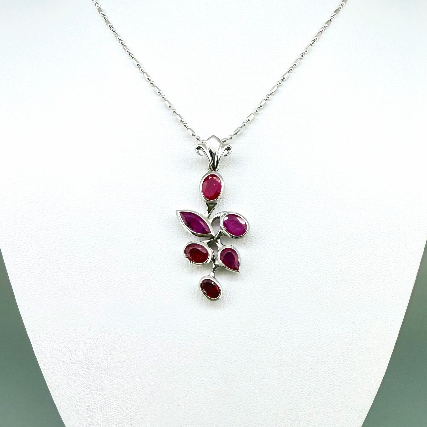 Handcrafted white-gold-plated silver pendant with 4.44 ct natural rubies in a floral design.