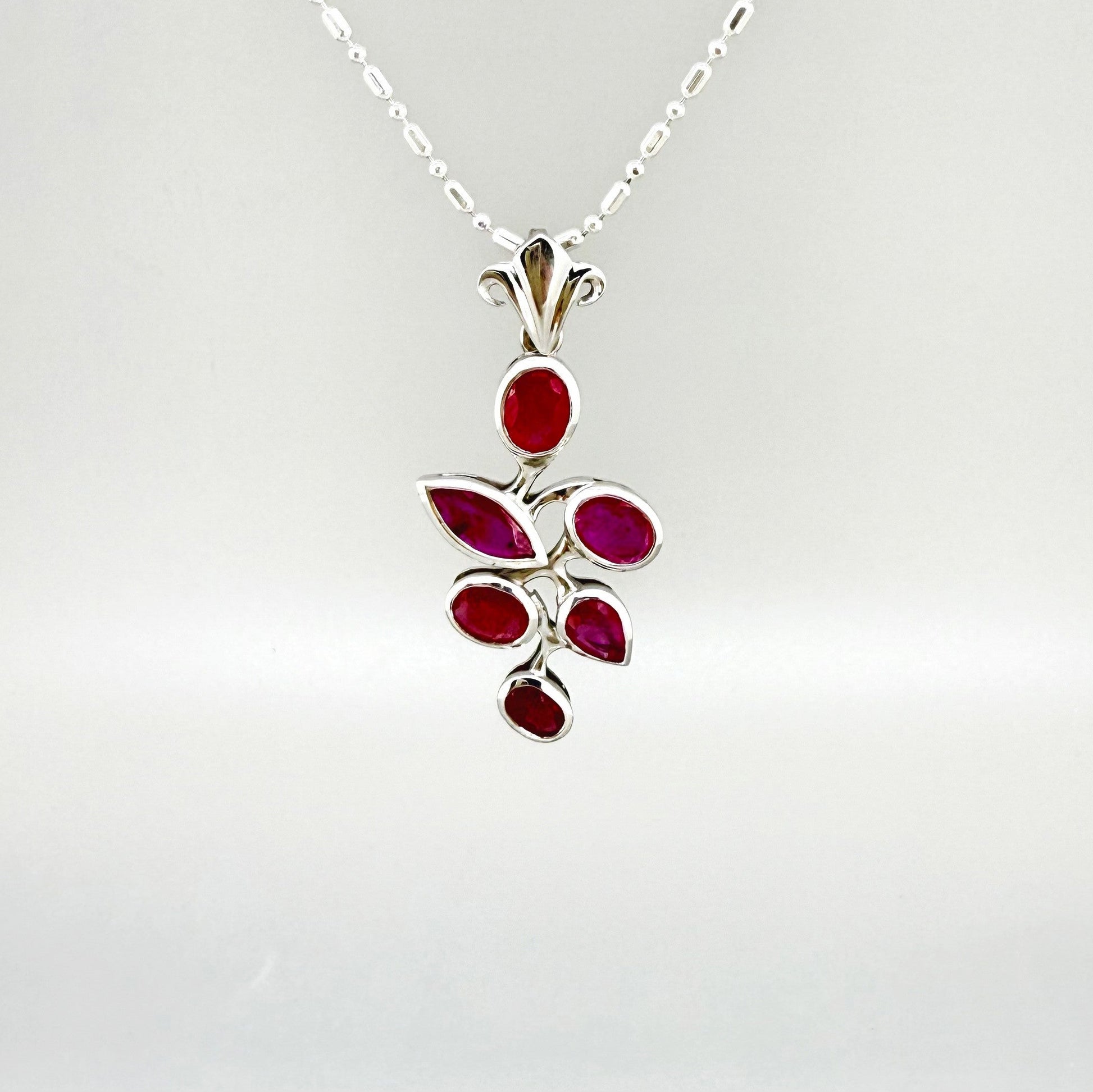 Handcrafted white-gold-plated silver pendant with 4.44 ct natural rubies in a floral design.