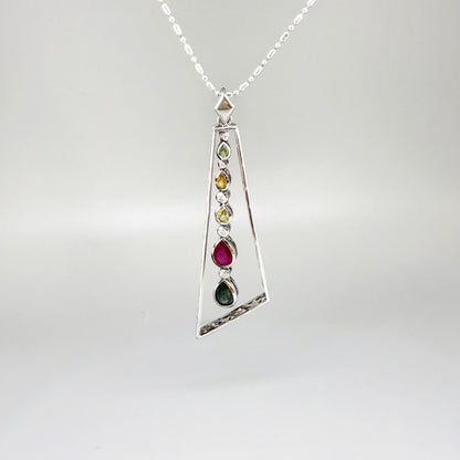 Handmade white gold plated silver pendant featuring 1.97 ct sapphires and 1.32 ct rubies in a modern geometric design with a freely moving gemstone strand.