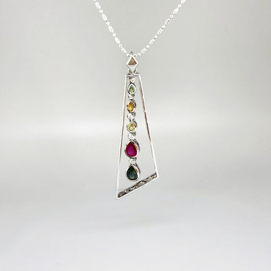 Handmade white gold plated silver pendant featuring 1.97 ct sapphires and 1.32 ct rubies in a modern geometric design with a freely moving gemstone strand.