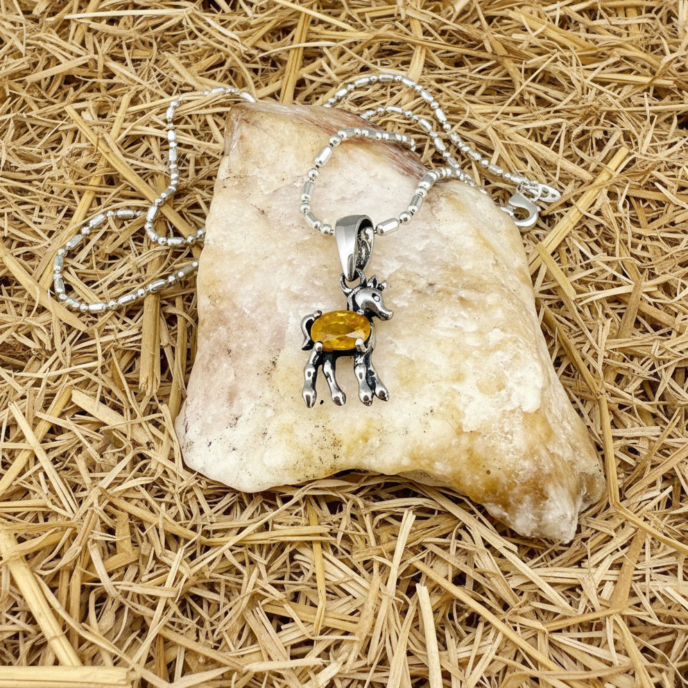 White-gold-plated silver horse pendant featuring a natural orange sapphire as the body.