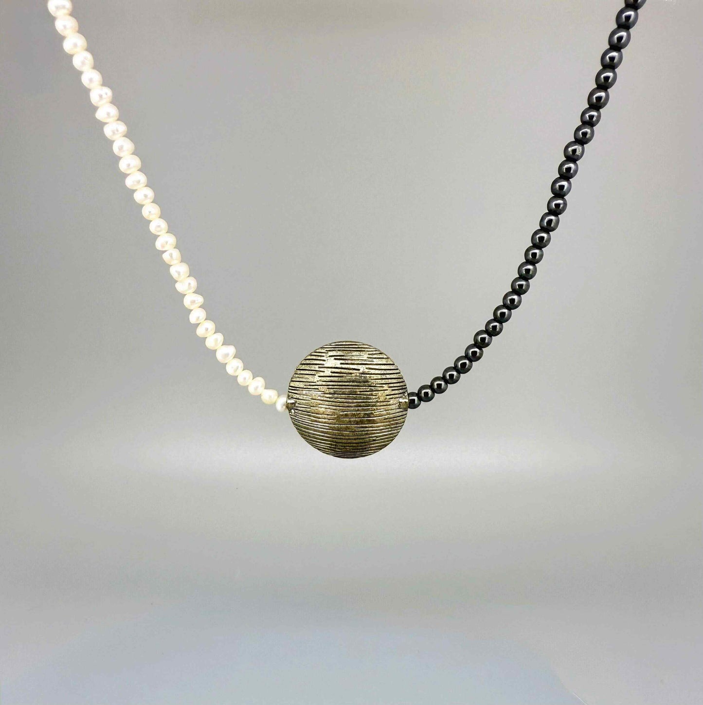 Hematite and cultured pearl necklace, 44 cm / 17.3 in long, featuring a large metallic centerpiece and contrasting light-dark design.