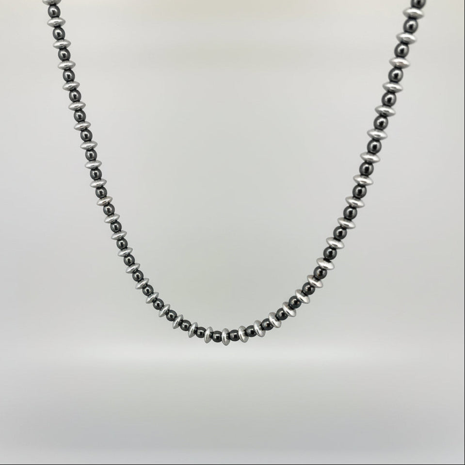 Hematite beaded necklace, 42 cm / 16.5 in long, featuring metallic silver-grey disc-shaped beads on a wooden background.