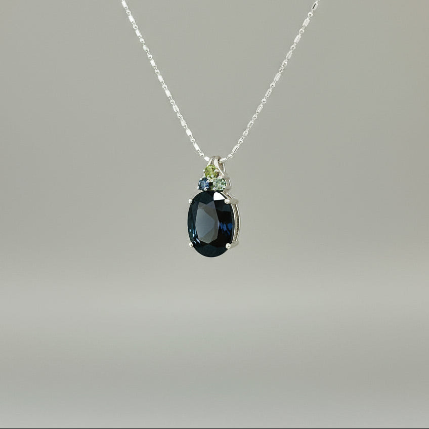 Elegant white gold plated silver pendant with 12.87 ct natural sapphires — one large central gem and three smaller accent stones.