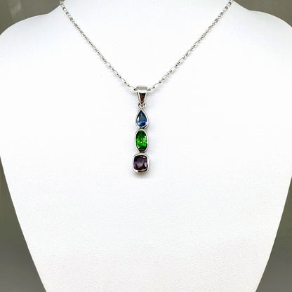 Handcrafted three-pendant gemstone necklace with sapphires, ruby, spinel, and tsavorite (5.81 ct total) on a black leather cord — modular design in white-gold-plated silver.