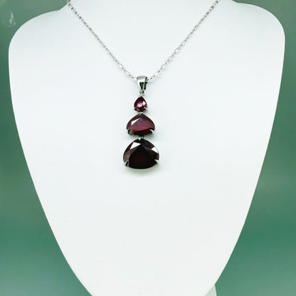 Necklace with a ruby gemstone pendant on a white mannequin bust against a green background