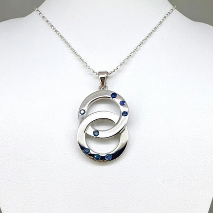 Handcrafted white gold plated silver pendant with 1.14 ct blue sapphires in circular design, symbolizing harmony and elegance.