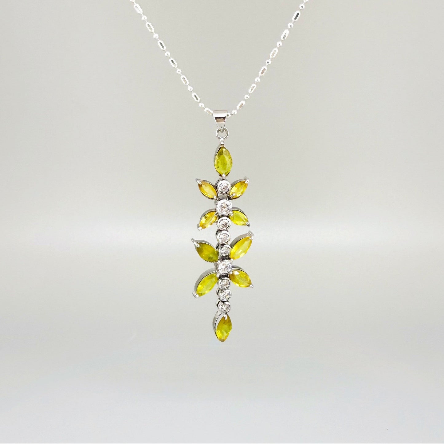 Handcrafted pendant with natural yellow sapphires (7.37 ct) and cubic zirconia in white-gold-plated silver leaf design, shown with matching earrings.