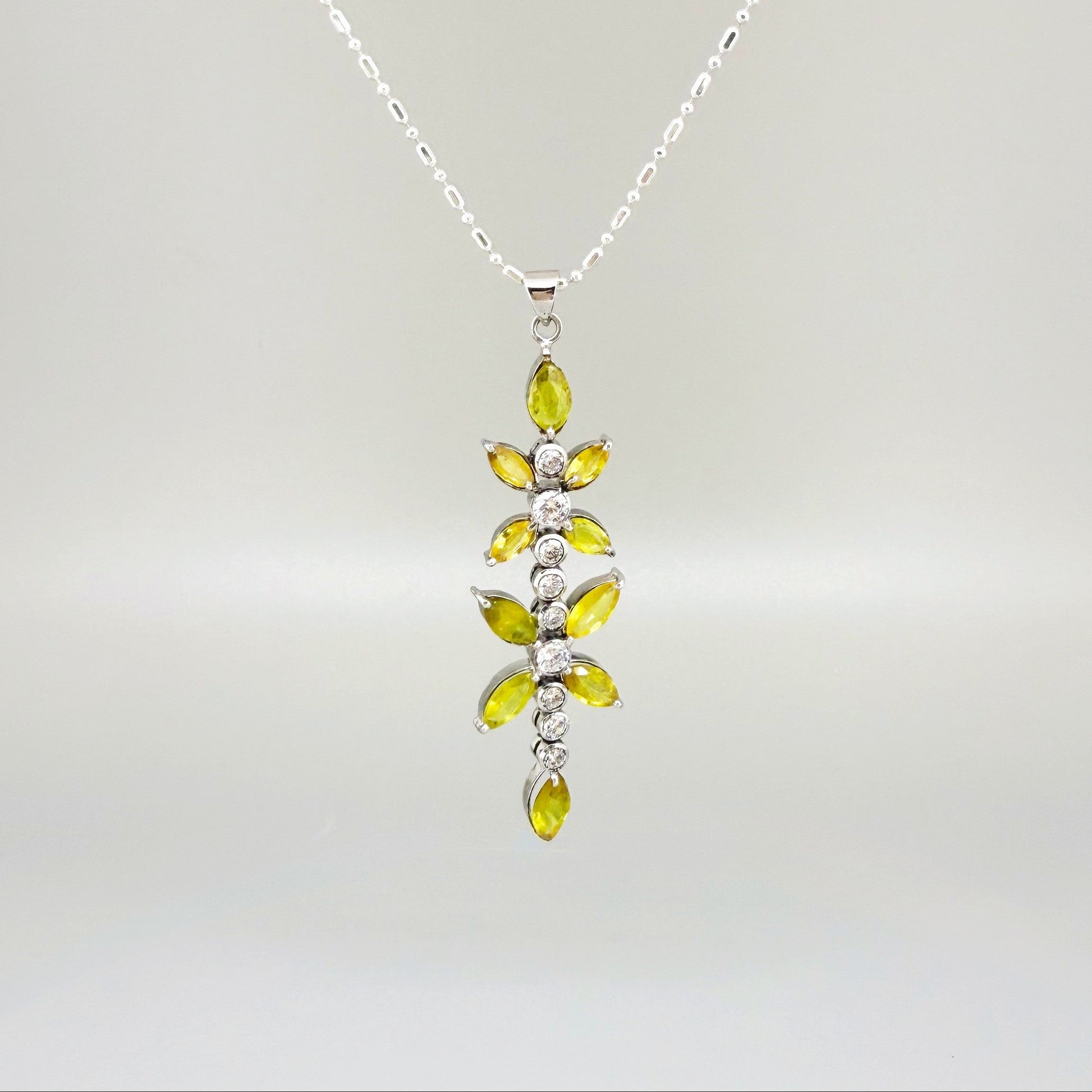 Handcrafted pendant with natural yellow sapphires (7.37 ct) and cubic zirconia in white-gold-plated silver leaf design, shown with matching earrings.