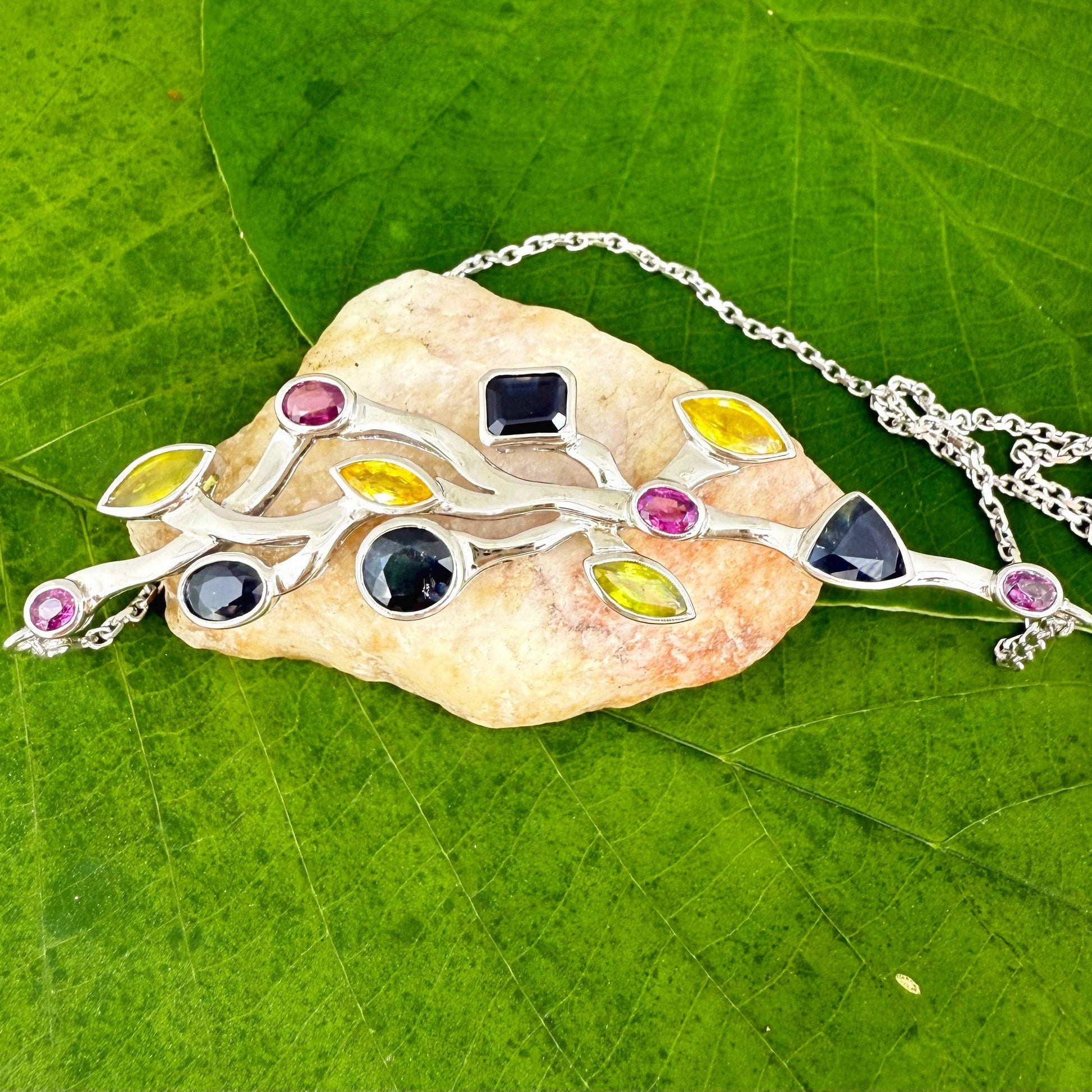 Handmade necklace in white-gold-plated silver featuring 13.89 ct natural sapphires and tourmalines in multicolor hues — artistic design with integrated chain.