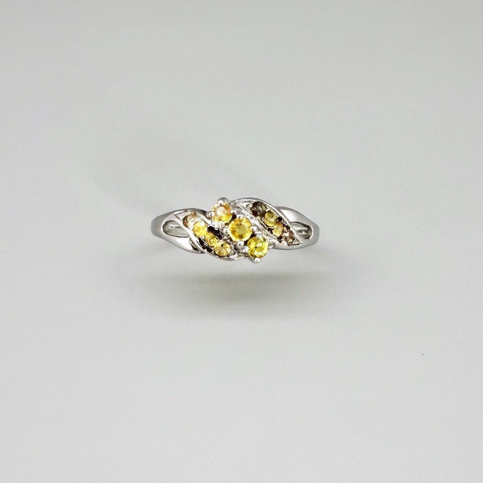 White gold plated sterling silver ring featuring two marquise-cut yellow sapphires in an elegant bypass setting.