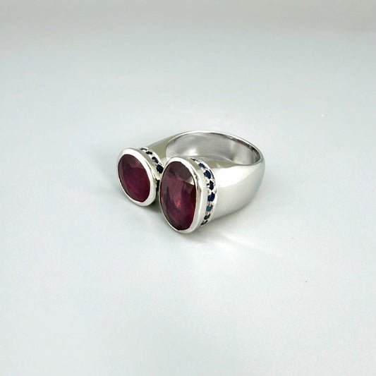 Ruby and sapphire bypass ring in white gold plated sterling silver, featuring two natural red rubies framed by blue sapphires in an open design, elegant and bold style.