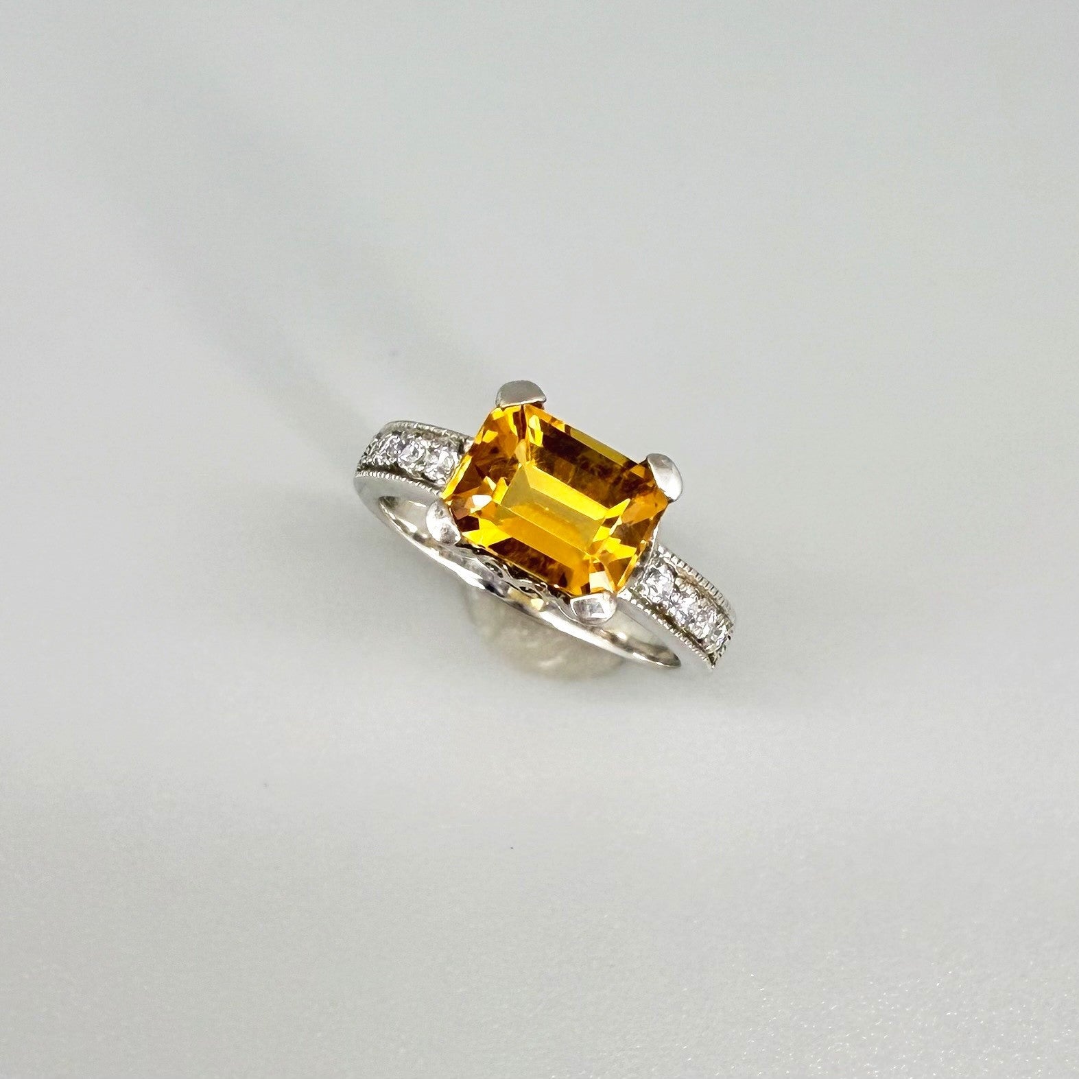 Citrine and CZ ring in white gold plated sterling silver, featuring a faceted golden gemstone framed by clear cubic zirconia, elegant and radiant design.