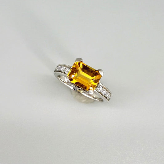 Citrine and CZ ring in white gold plated sterling silver, featuring a faceted golden gemstone framed by clear cubic zirconia, elegant and radiant design.