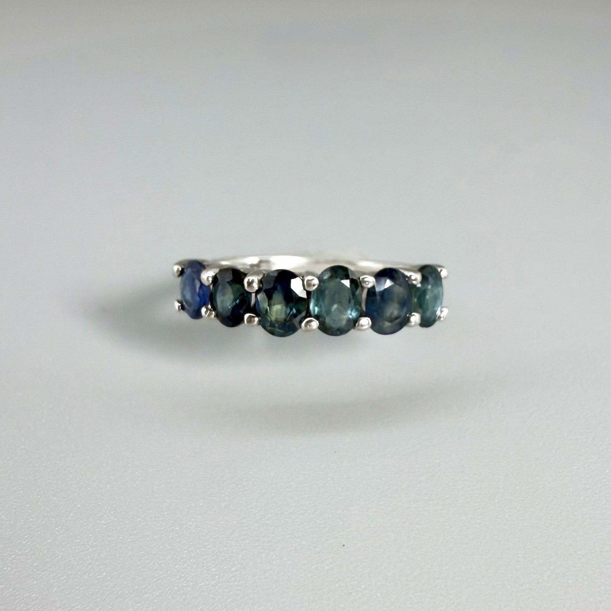 Blue sapphire ring in white gold plated sterling silver on neutral background