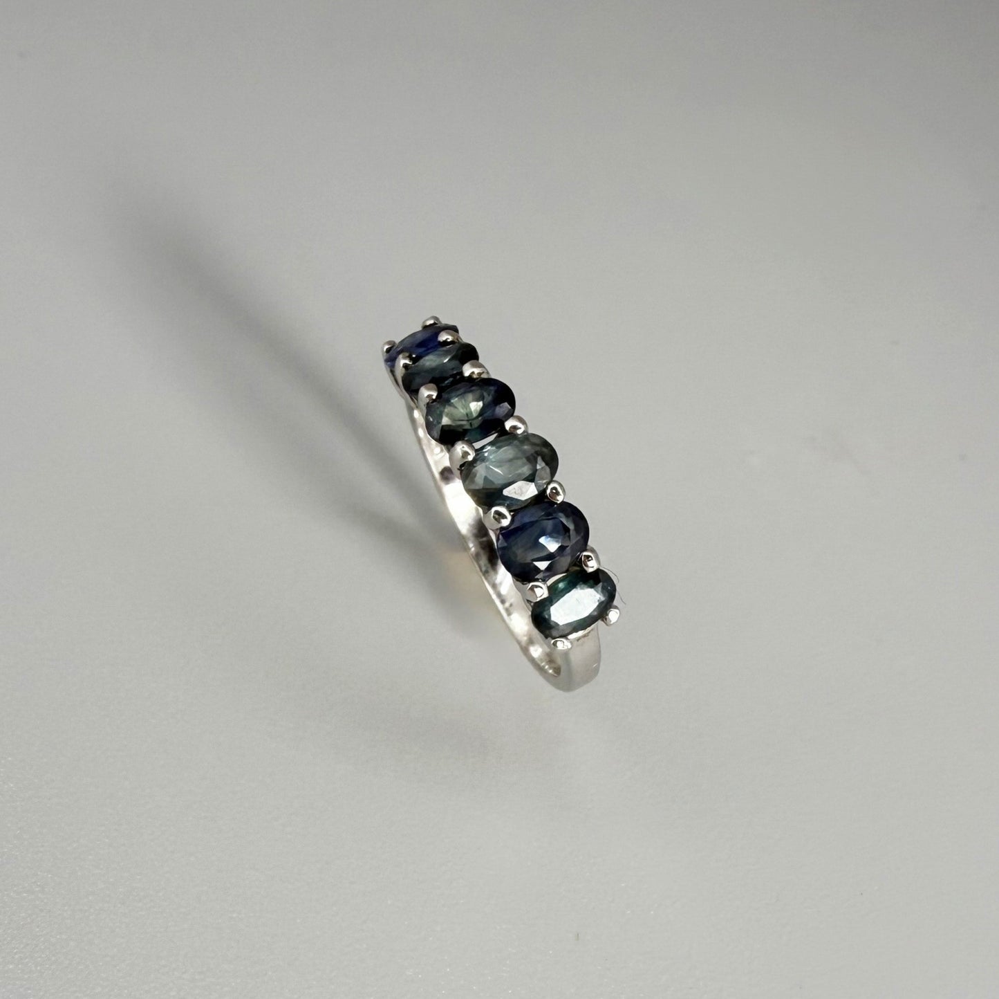 Blue sapphire ring in white gold plated sterling silver on neutral background