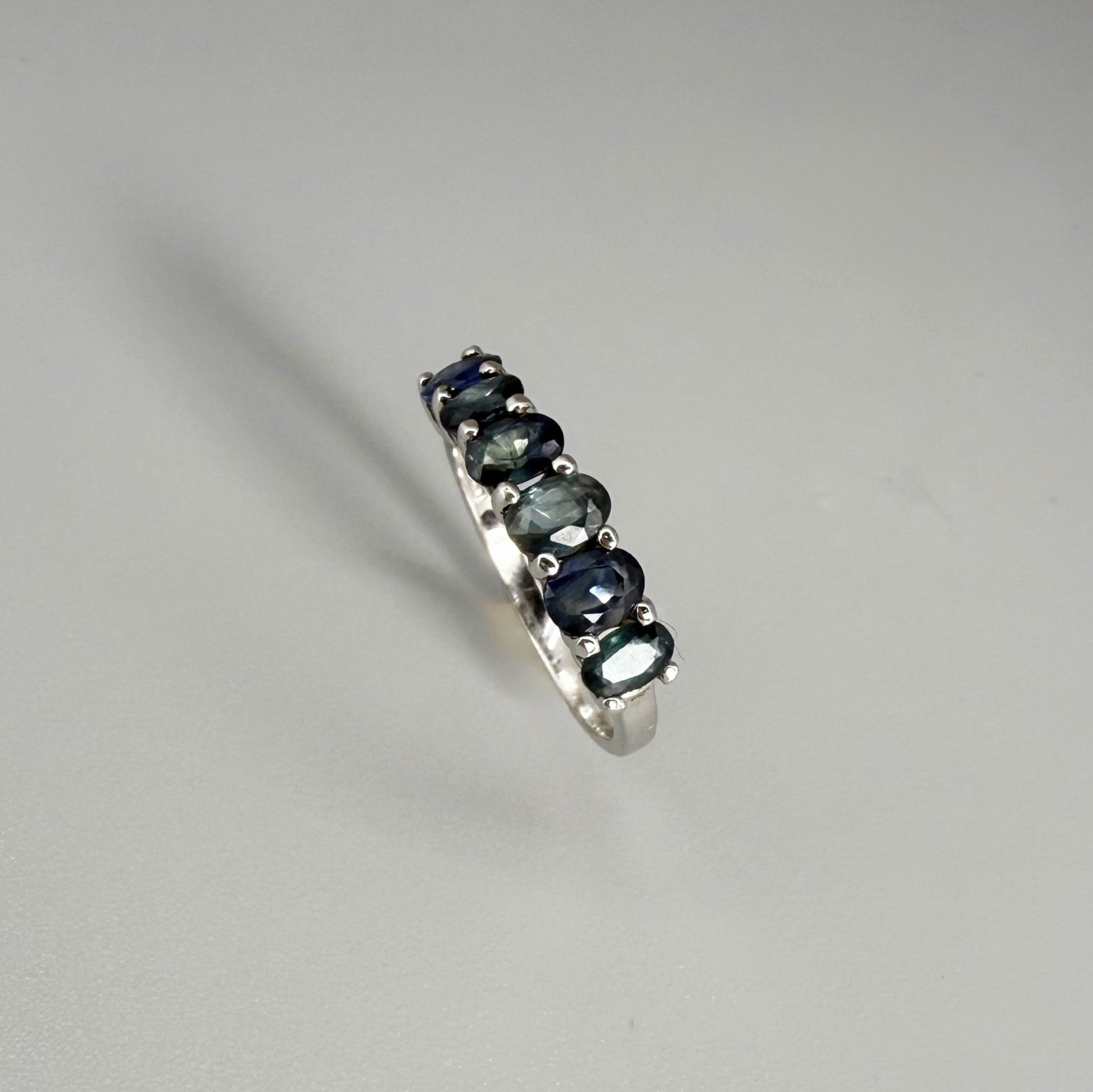 Blue sapphire ring in white gold plated sterling silver on neutral background