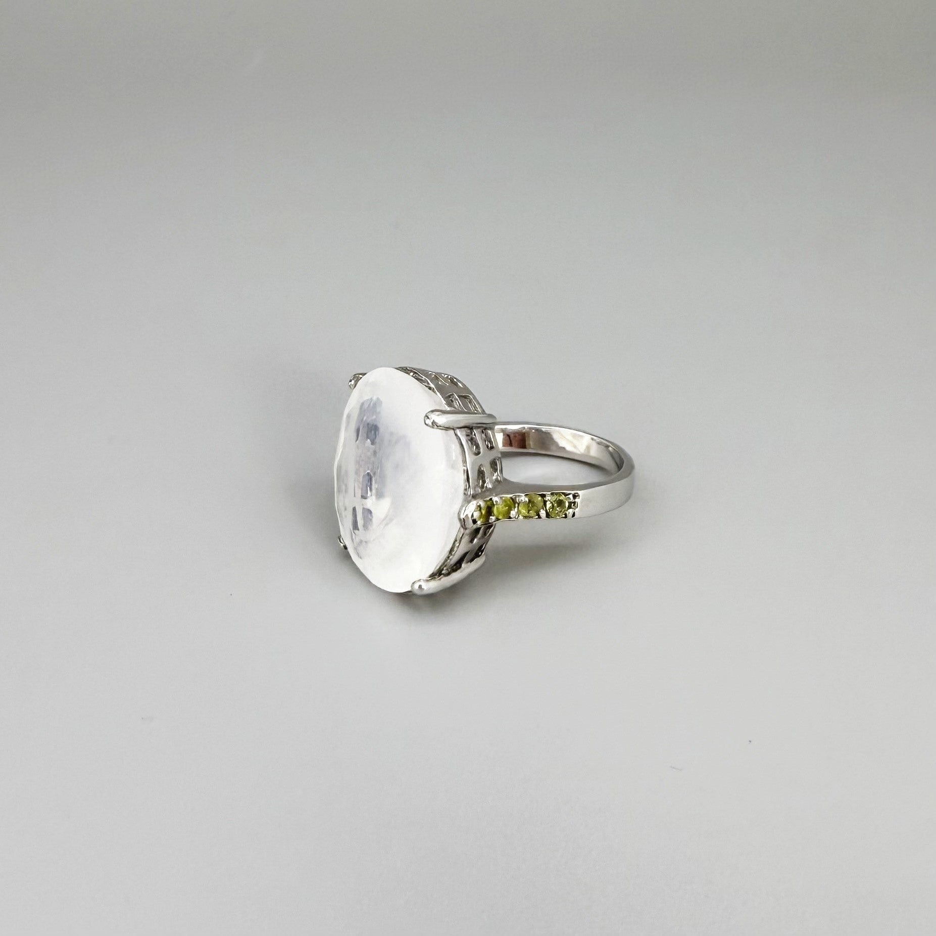 White quartz and sapphire ring in white gold plated sterling silver, featuring a faceted clear gemstone framed by blue sapphires, elegant and refined design.