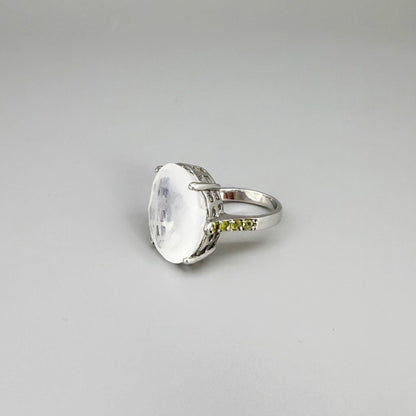 White quartz and sapphire ring in white gold plated sterling silver, featuring a faceted clear gemstone framed by blue sapphires, elegant and refined design.