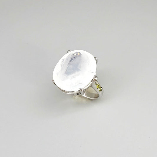White quartz and sapphire ring in white gold plated sterling silver, featuring a faceted clear gemstone framed by blue sapphires, elegant and refined design.