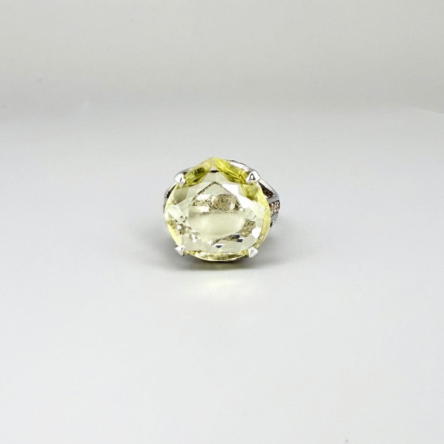 White gold plated sterling silver ring featuring a lemon quartz gemstone surrounded by orange sapphires in a halo design.