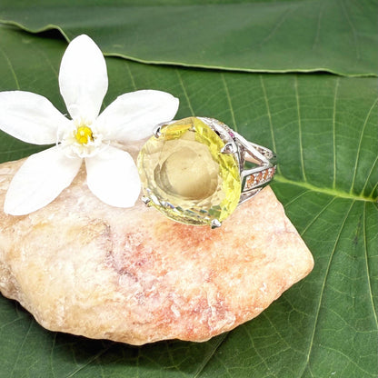 White gold plated sterling silver ring featuring a lemon quartz gemstone surrounded by orange sapphires in a halo design.
