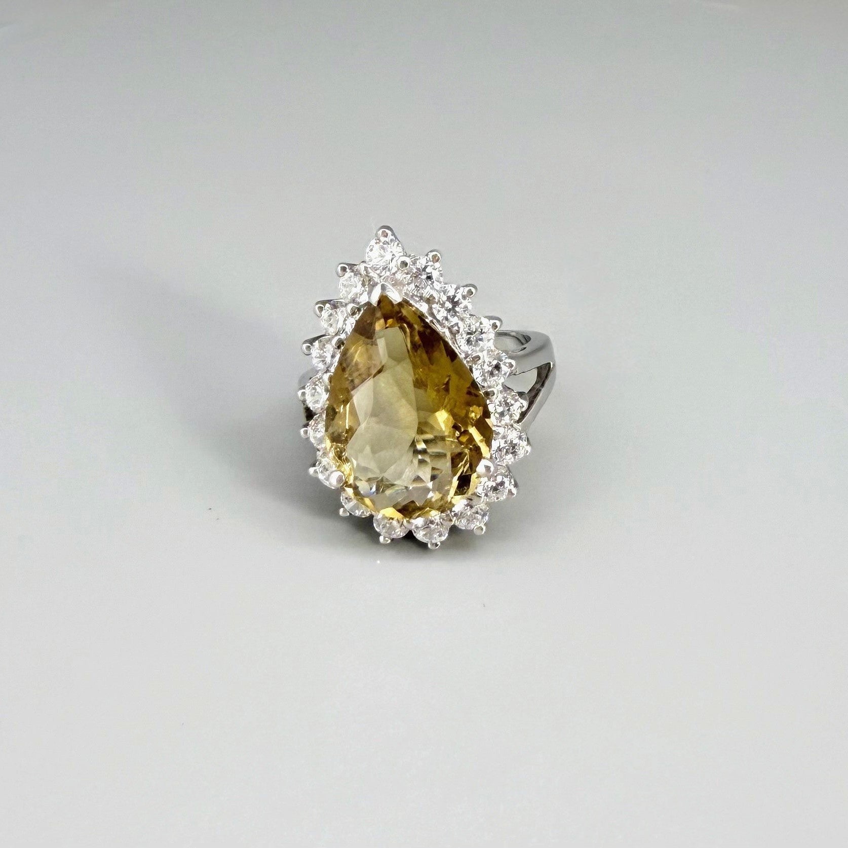 Citrine and CZ ring in white gold plated sterling silver, featuring a pear-shaped golden-yellow gemstone surrounded by clear cubic zirconia halo, elegant and refined design