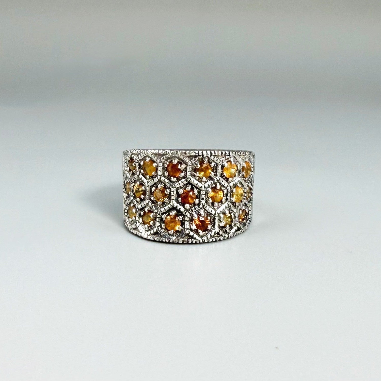 Wide band orange sapphire ring in white gold plated sterling silver featuring faceted sapphires in bright amber hues for a warm, elegant shine.