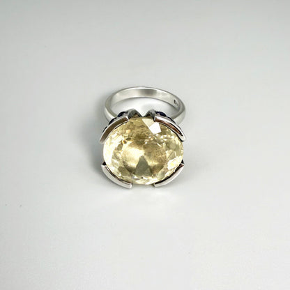 Lemon quartz and sapphire ring in white gold plated sterling silver, featuring a faceted yellow-green gemstone framed by deep blue sapphires, elegant and vibrant design.