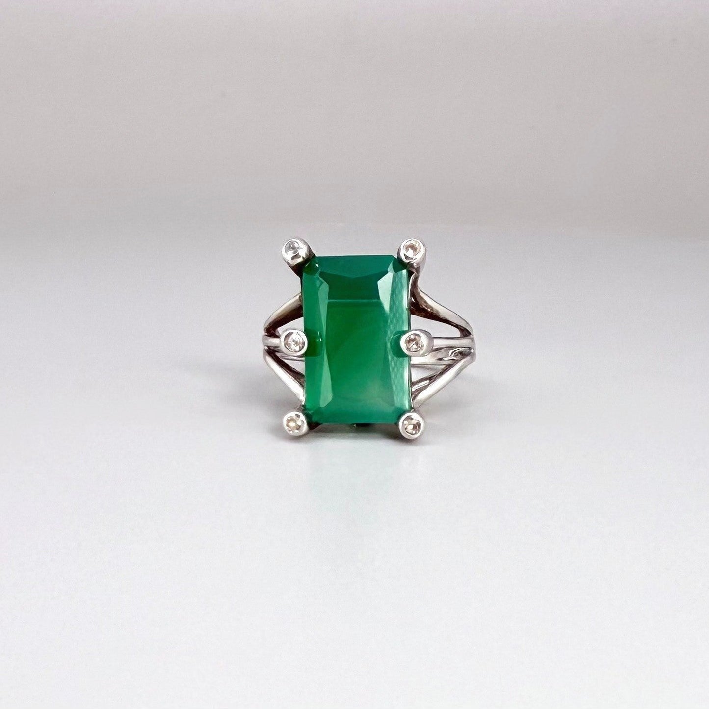 White gold plated sterling silver ring with emerald-cut green chalcedony, elegant solitaire design with soft natural glow.