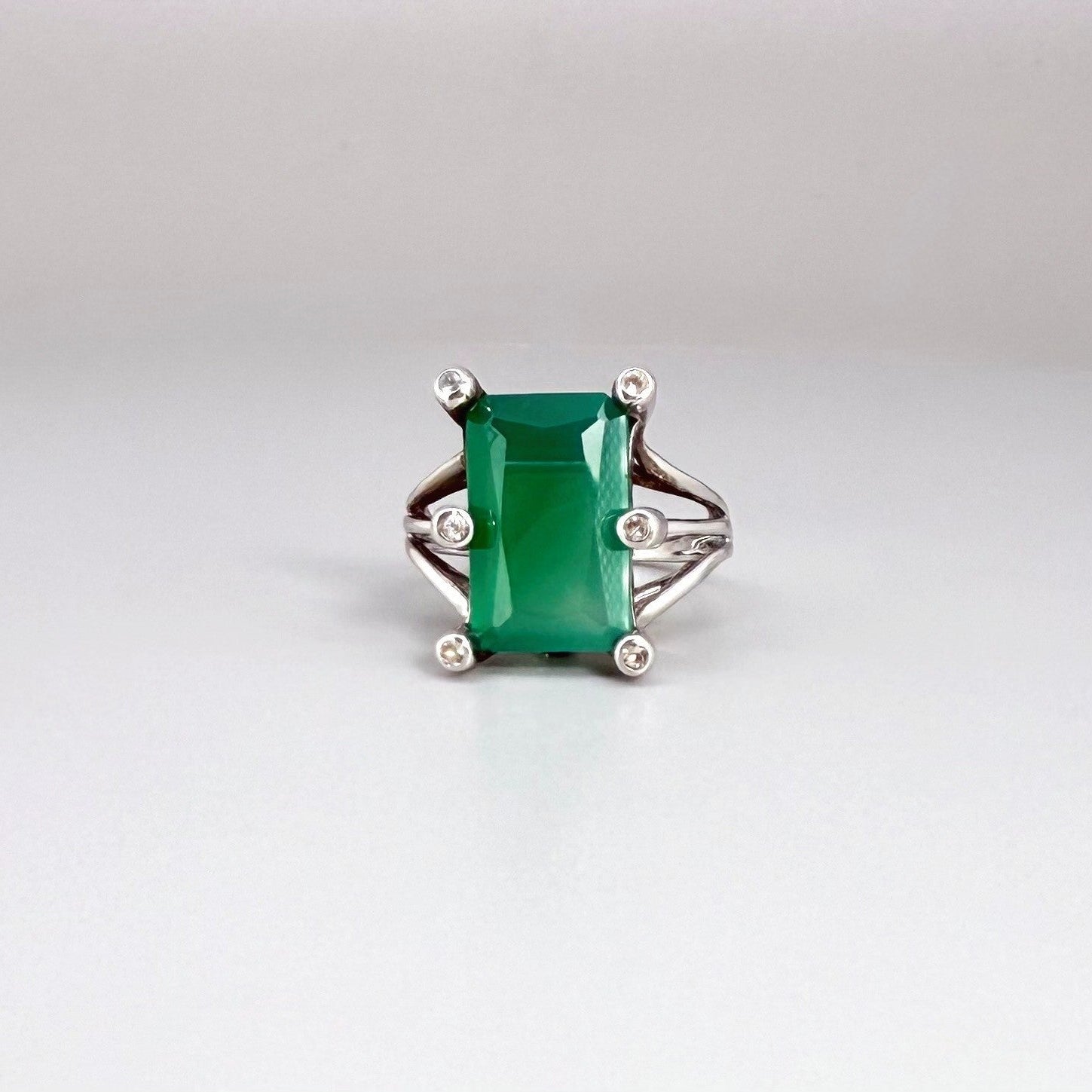White gold plated sterling silver ring with emerald-cut green chalcedony, elegant solitaire design with soft natural glow.