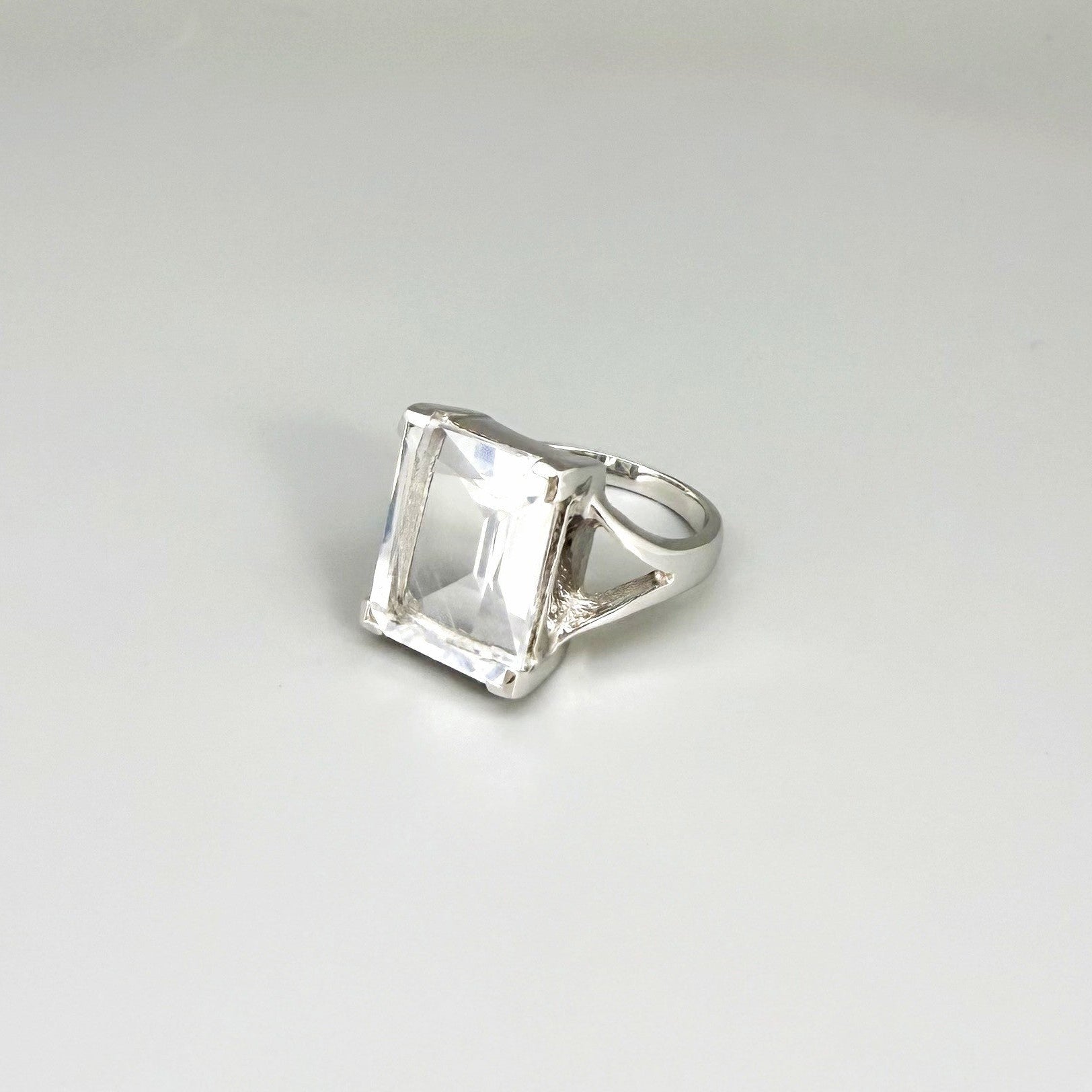 White quartz ring in white gold plated sterling silver, featuring a faceted clear gemstone with brilliant reflections, elegant and timeless design.