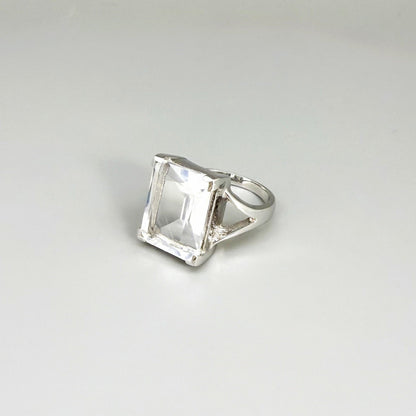White quartz ring in white gold plated sterling silver, featuring a faceted clear gemstone with brilliant reflections, elegant and timeless design.
