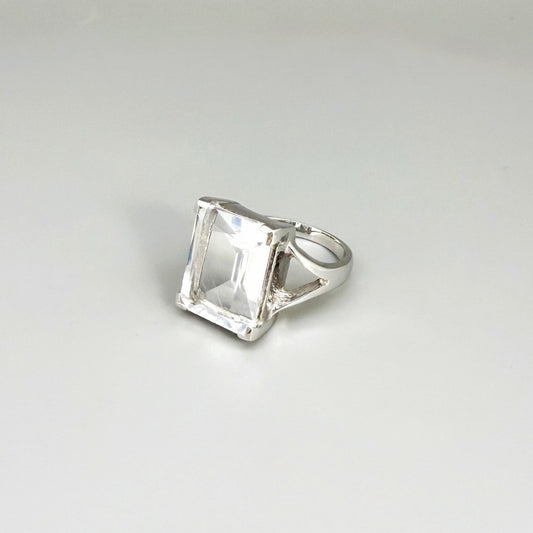 White quartz ring in white gold plated sterling silver, featuring a faceted clear gemstone with brilliant reflections, elegant and timeless design.