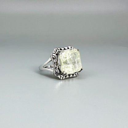 White gold plated sterling silver ring with natural light green emerald, detailed setting, and elegant, refined craftsmanship.